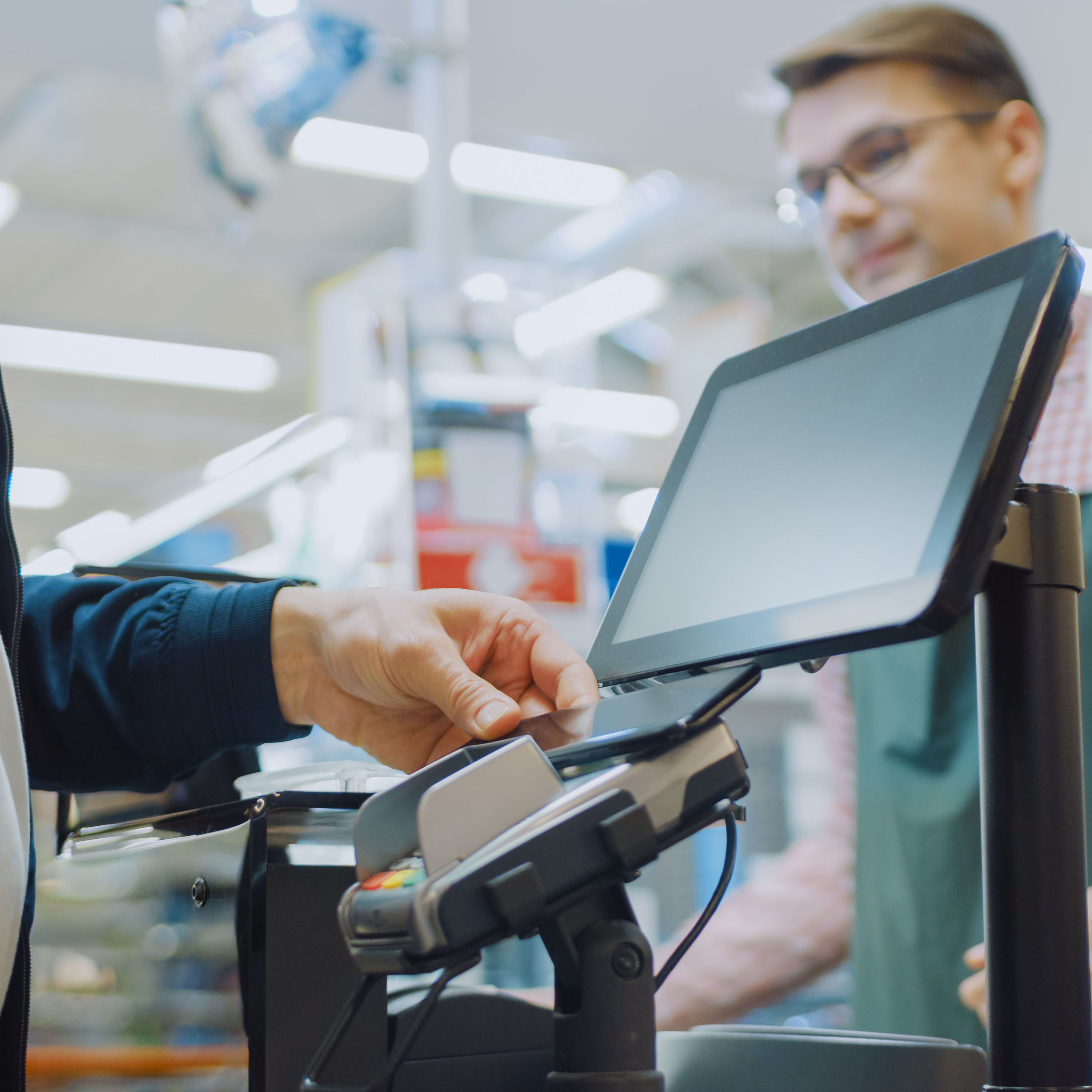 Mann zahlt mit seinem Handy an der Supermarktkasse.