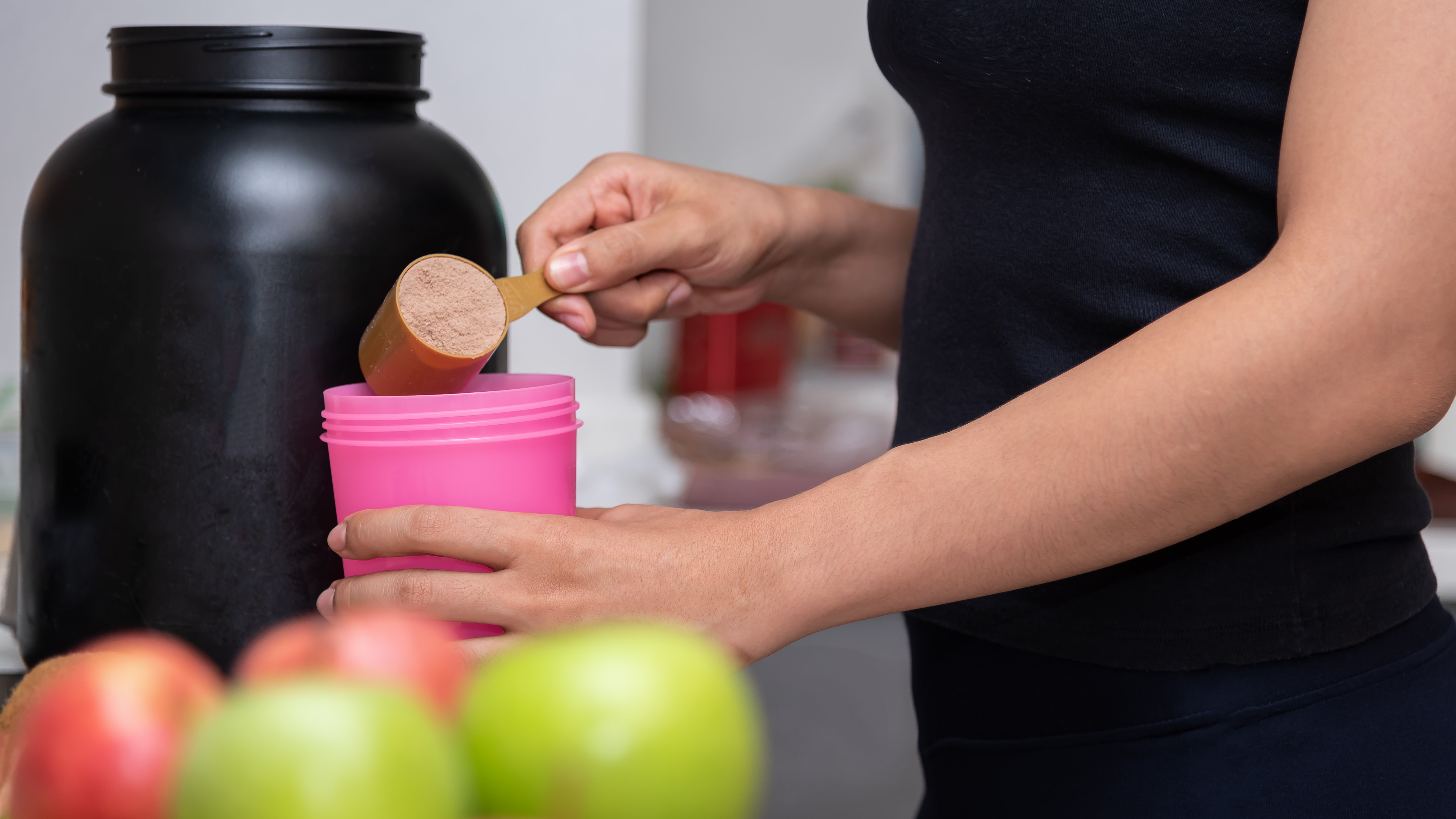 Frau bereitet Shake mit veganem Proteinpulver zu