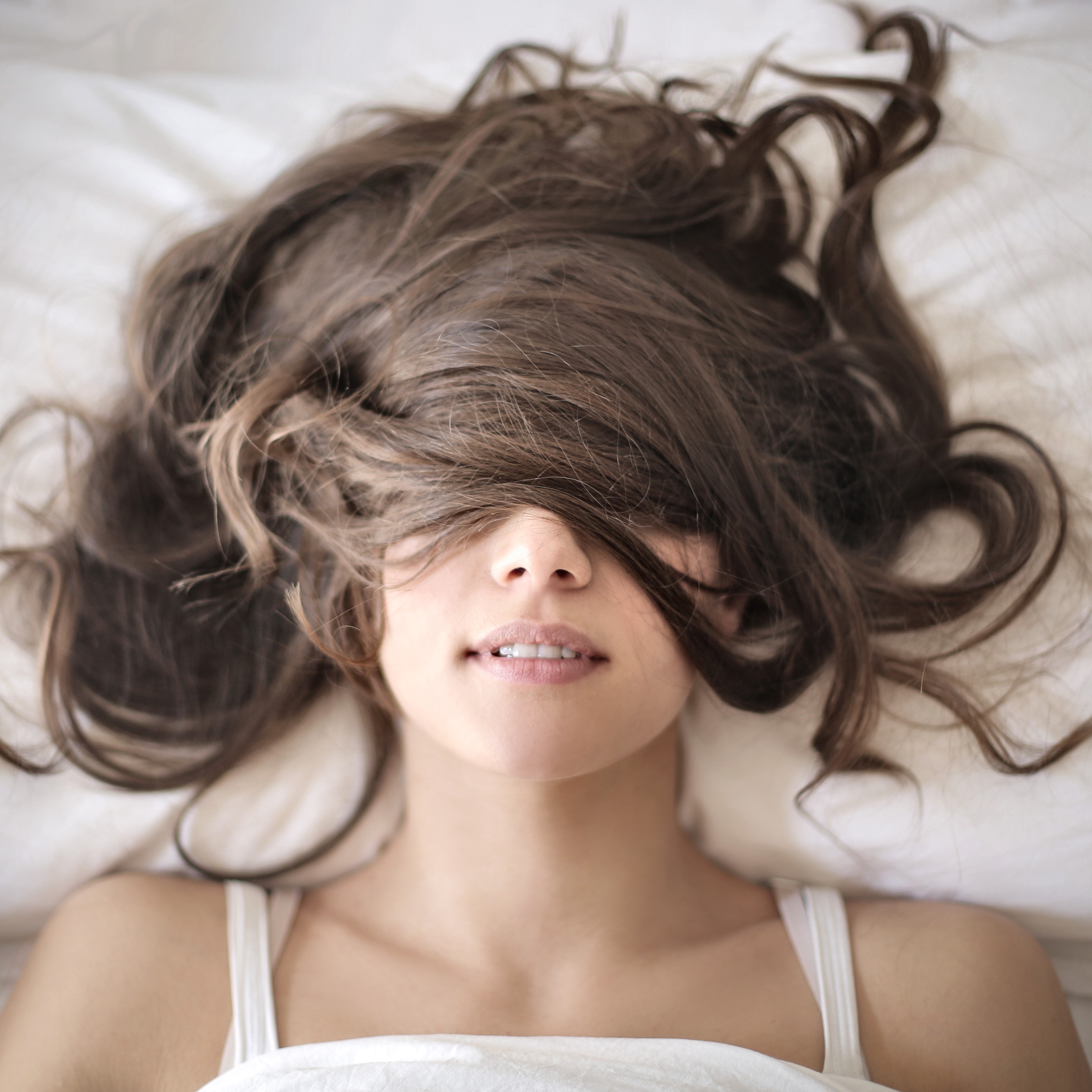 Frau liegt im Bett mit Haaren im Gesicht