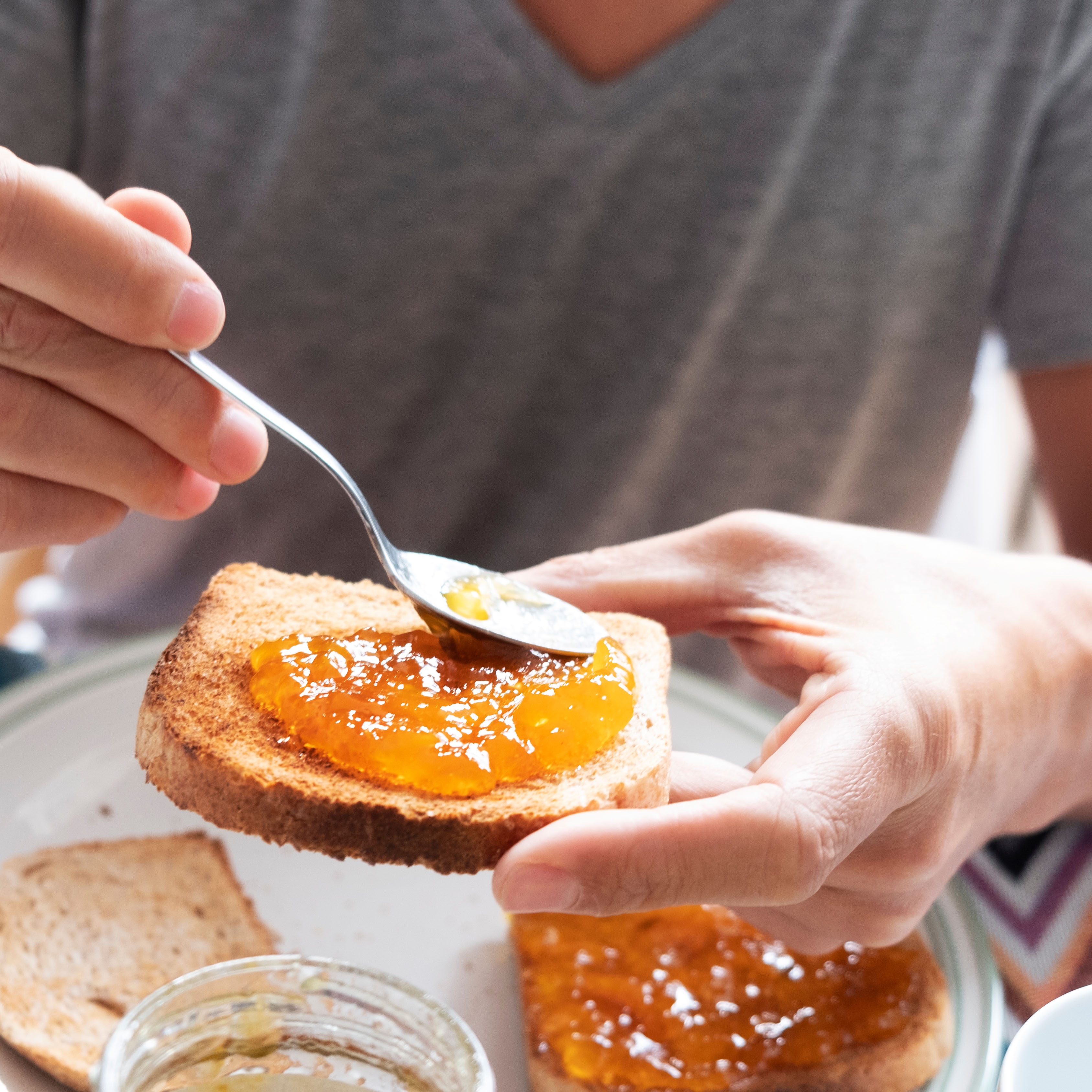 Mann schmiert Marmelade auf Brot