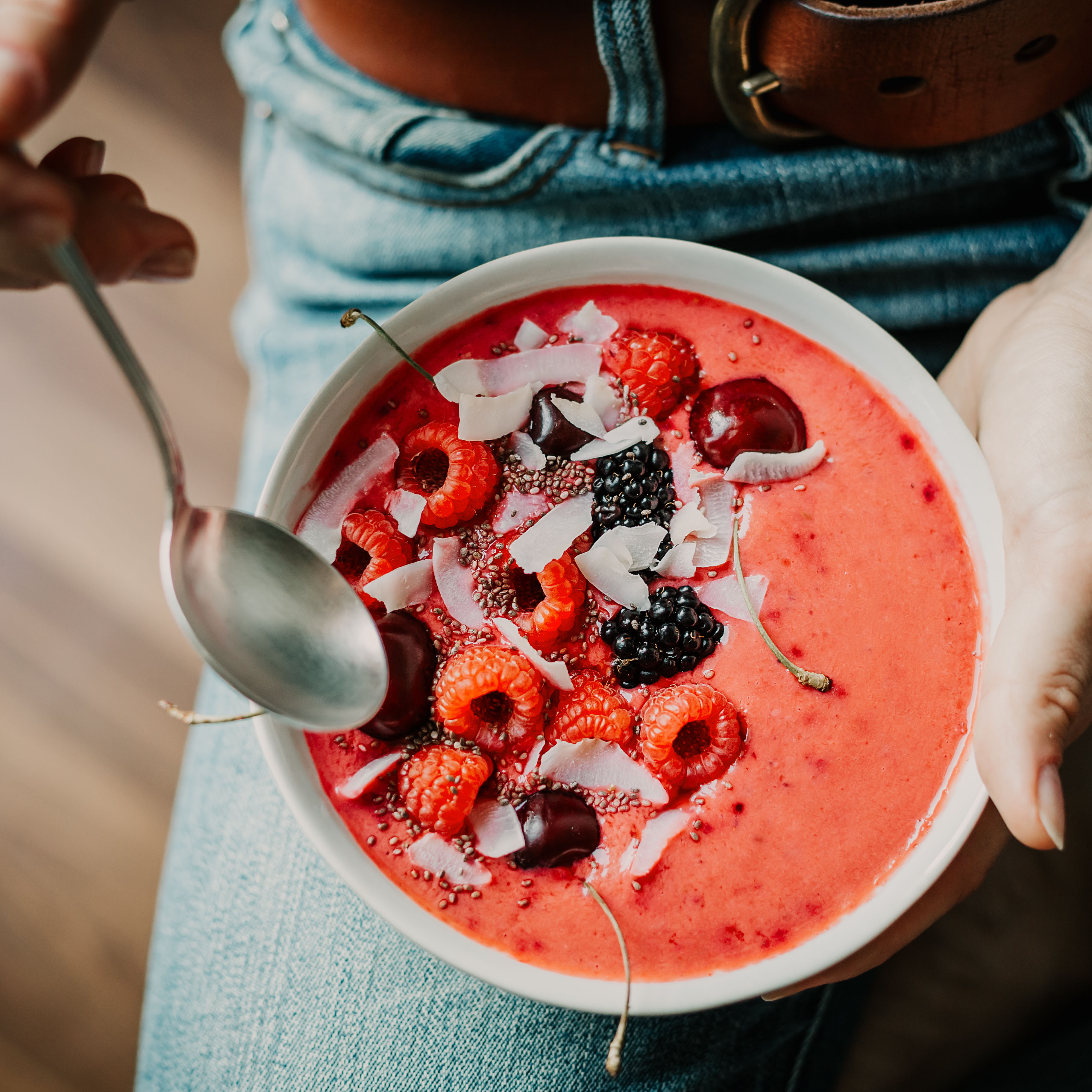 Frau isst Bowl mit roten Früchten