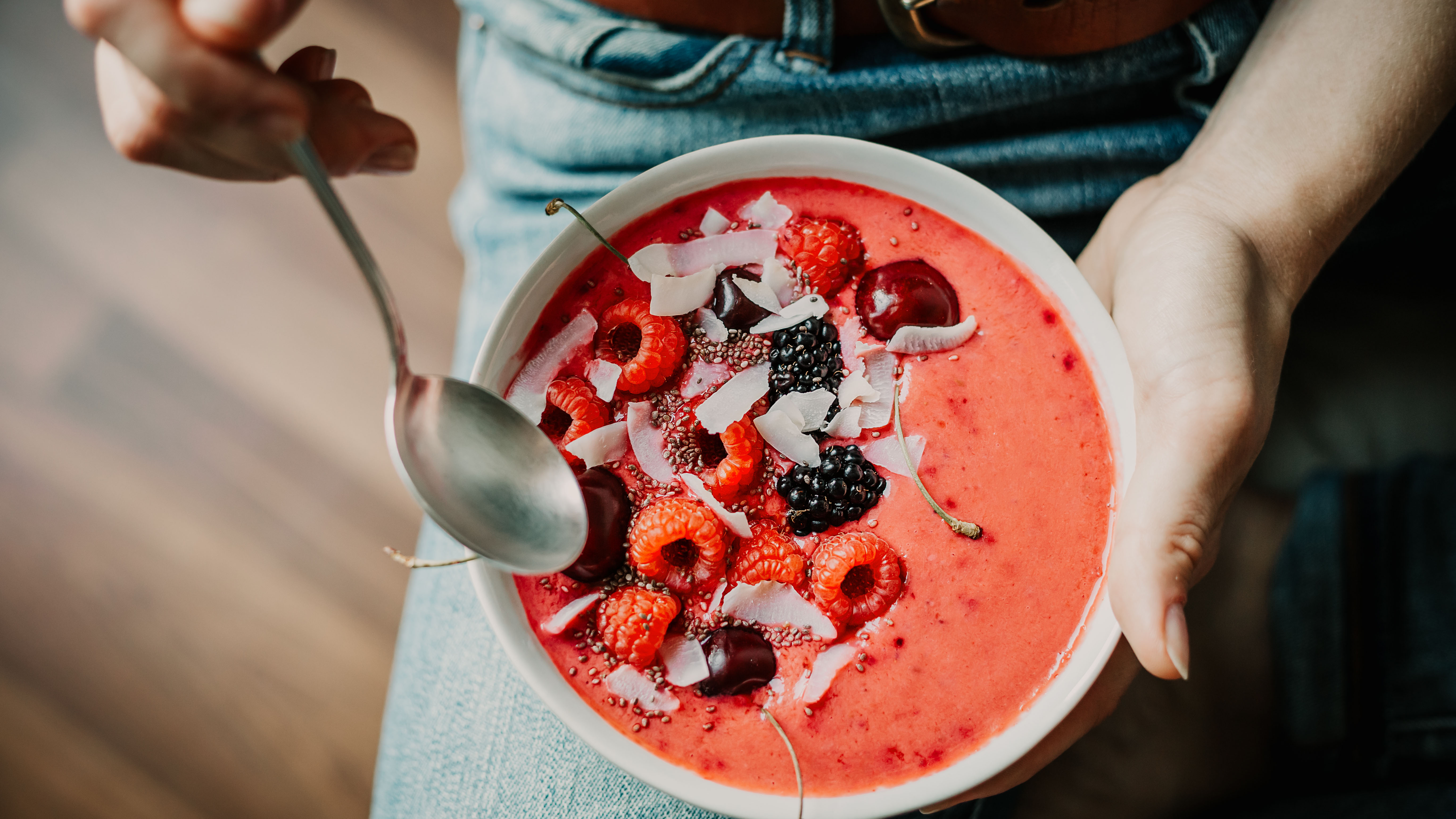 Frau isst Bowl mit roten Früchten