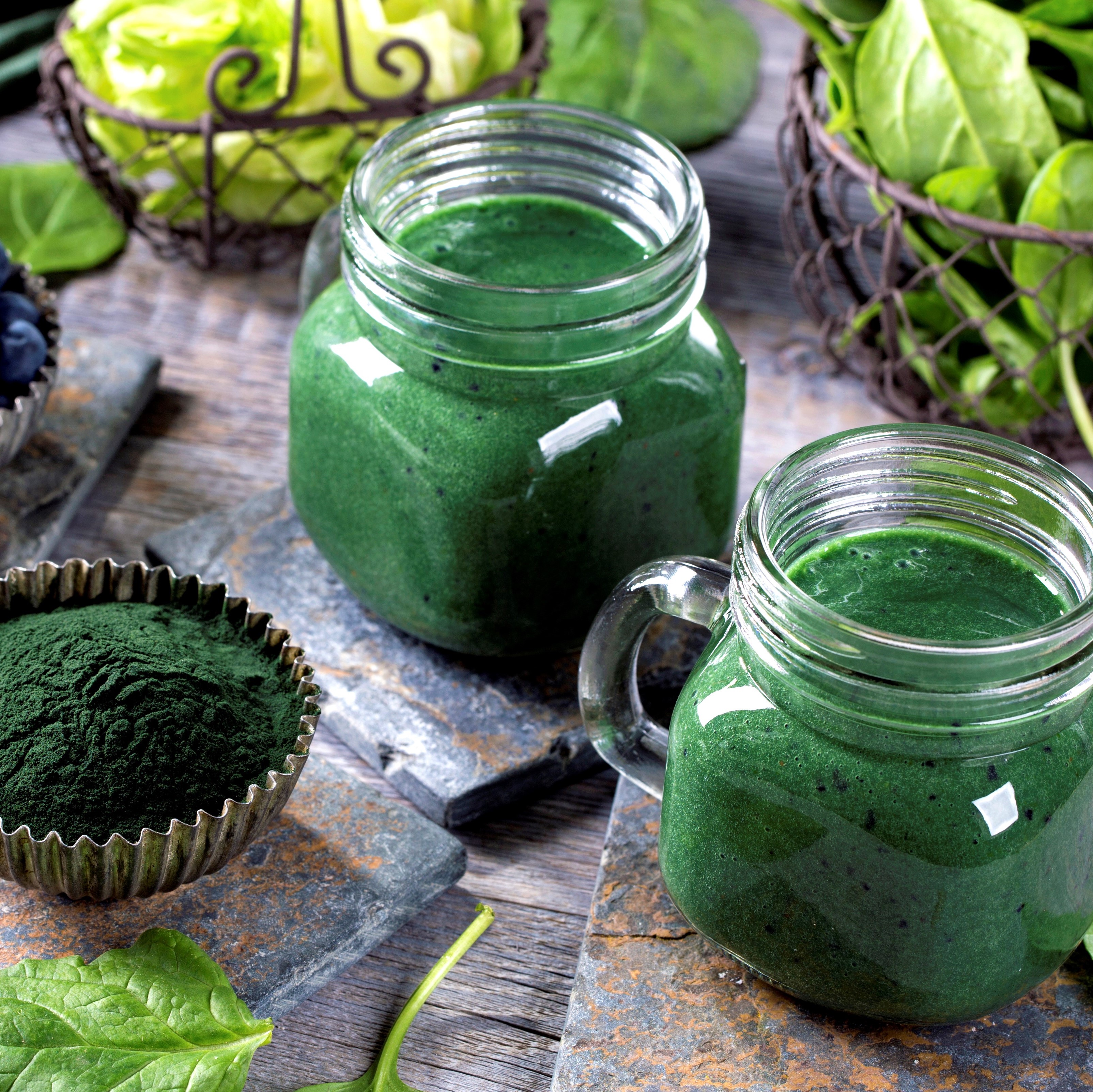 Spirulina in Gläsern und Spirulina-Pulver auf Holztisch