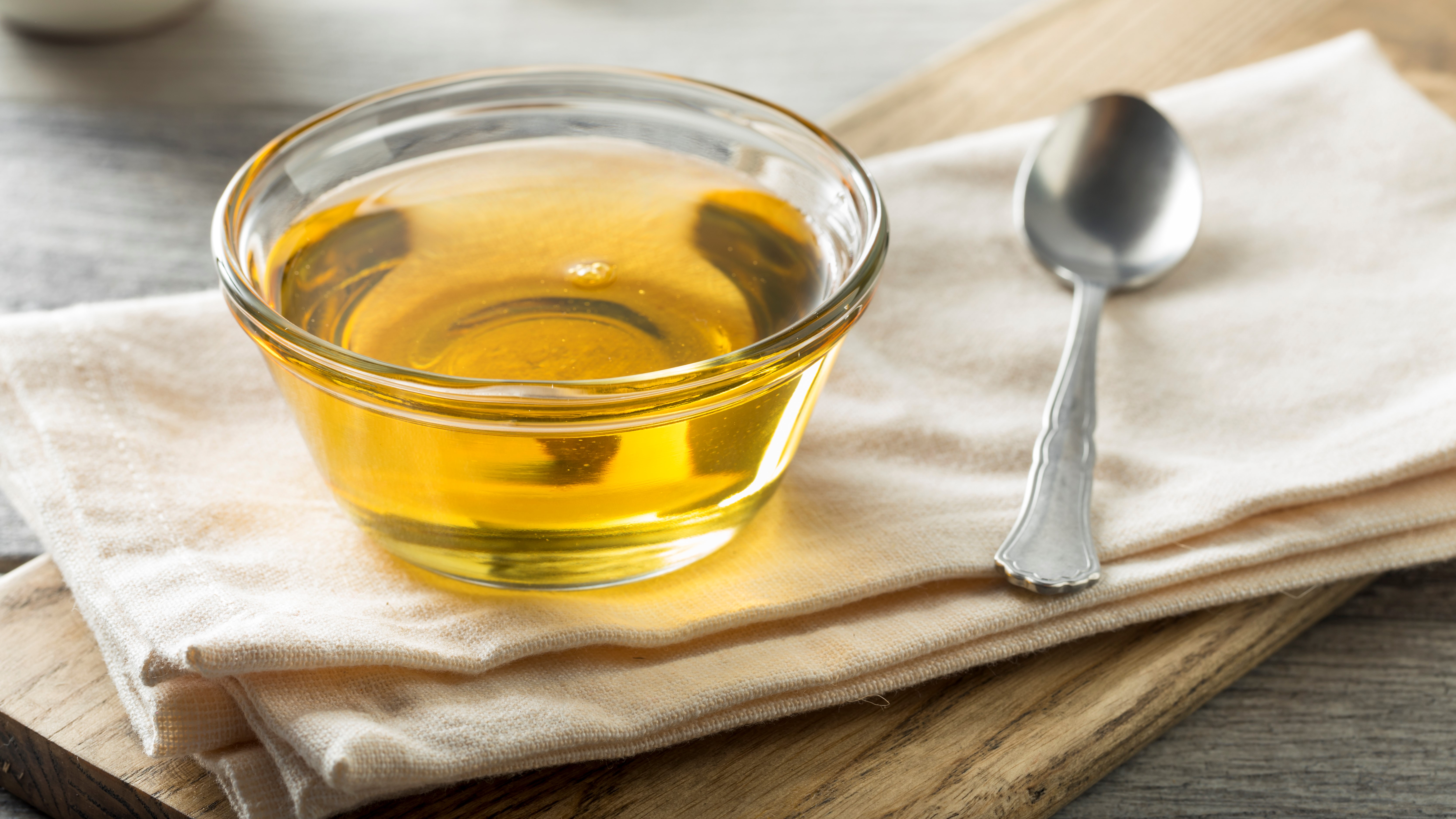 Agavendicksaft in Glasschale mit Löffel auf Holzbrett