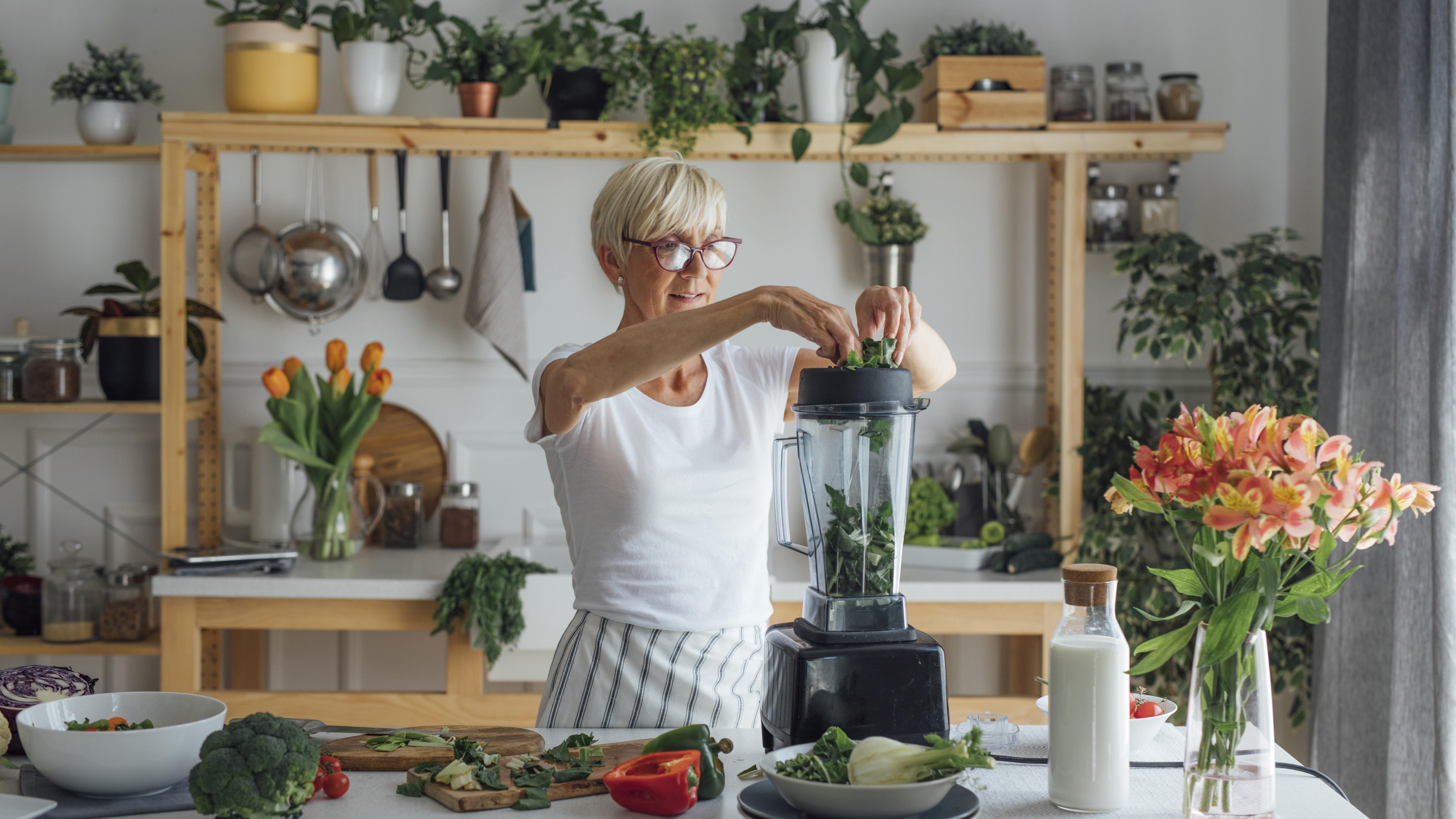 Dame bereitet einen grünen Smoothie im Mixer zu