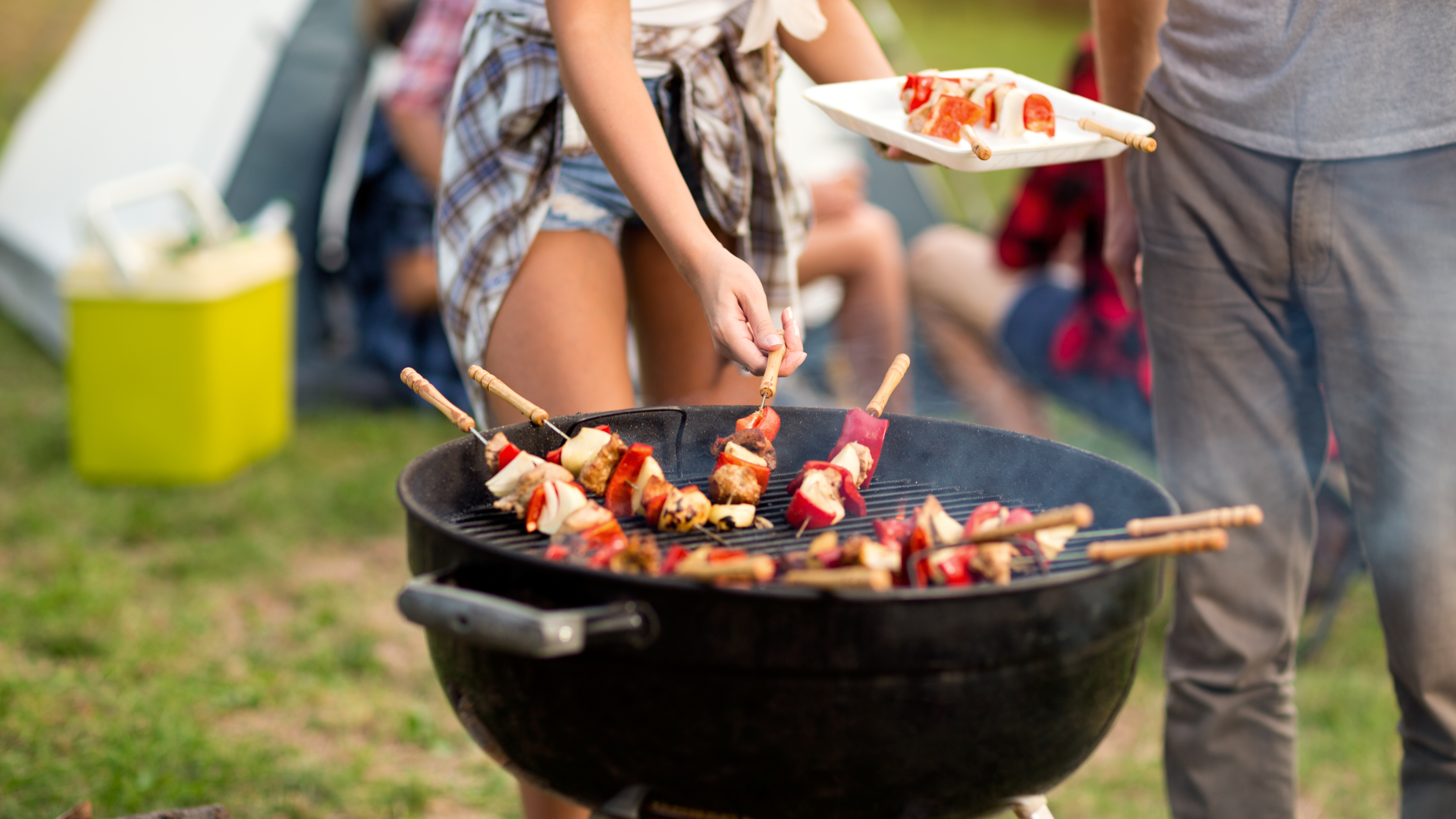 Frau steht auf dem Zeltplatz an einem Grill