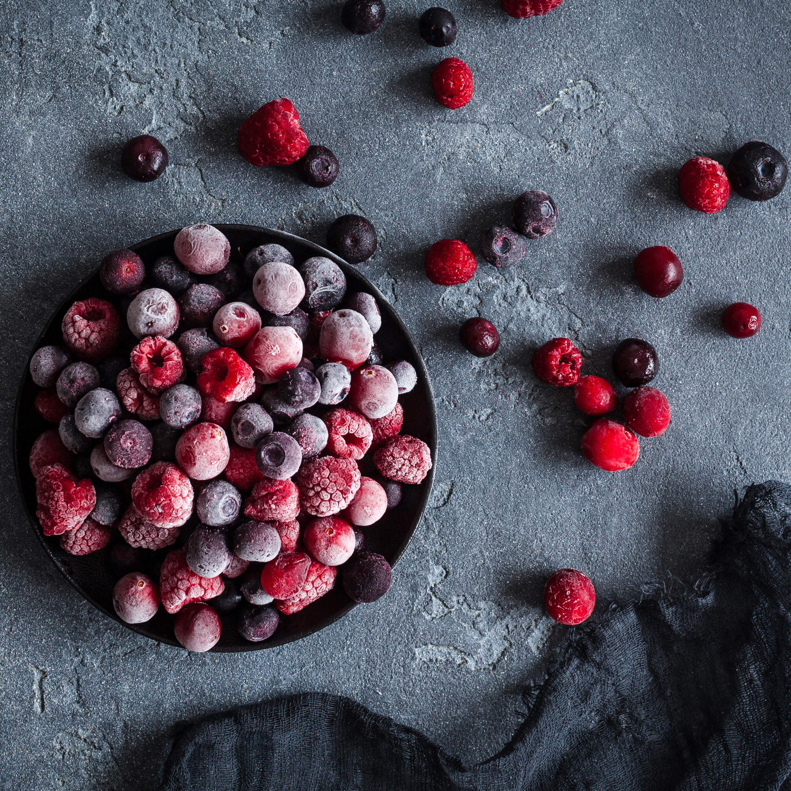 Gefrorene Beeren in einer dunklen Schale auf dunklem Hintergrund