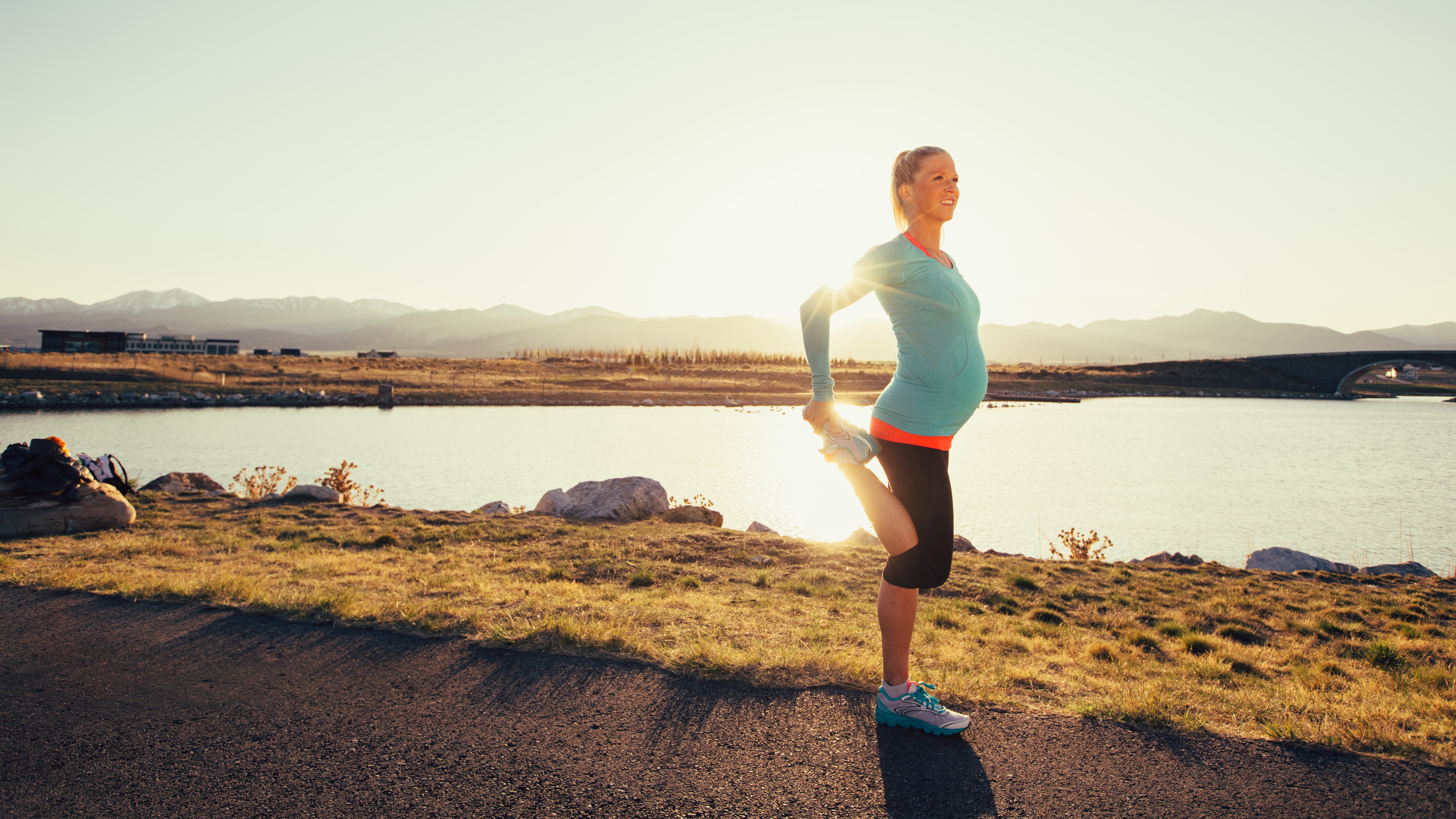 Frau macht Sport in der Schwangerschaft morgens am See