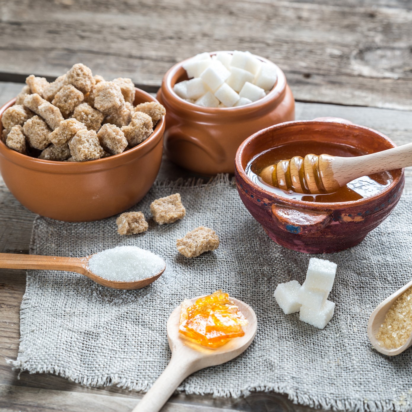 Honig, Stevia und Zucker in Tontöpfen, mit Löffeln