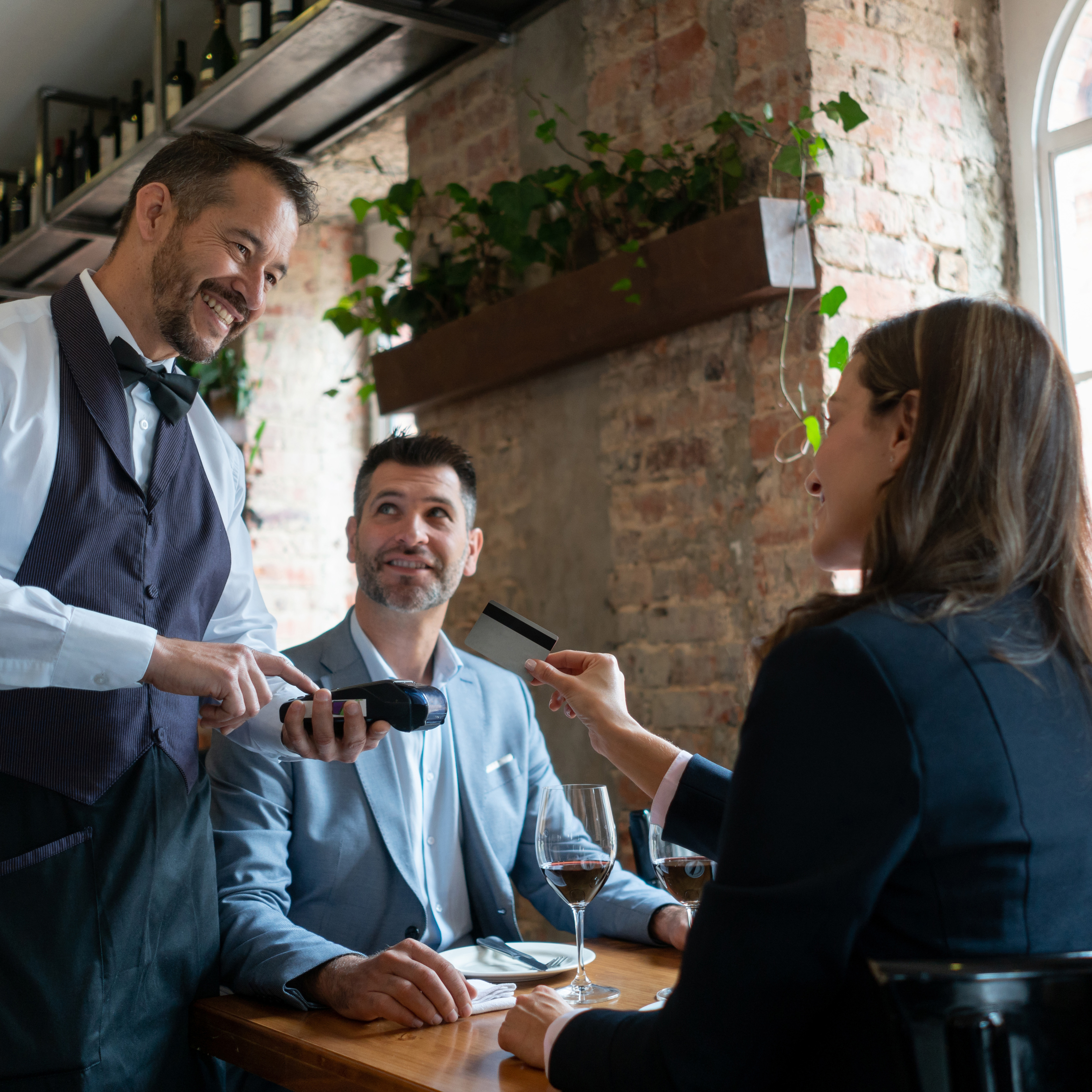 Eine Frau zahlt im Restaurant mit Karte beim Kellner. 