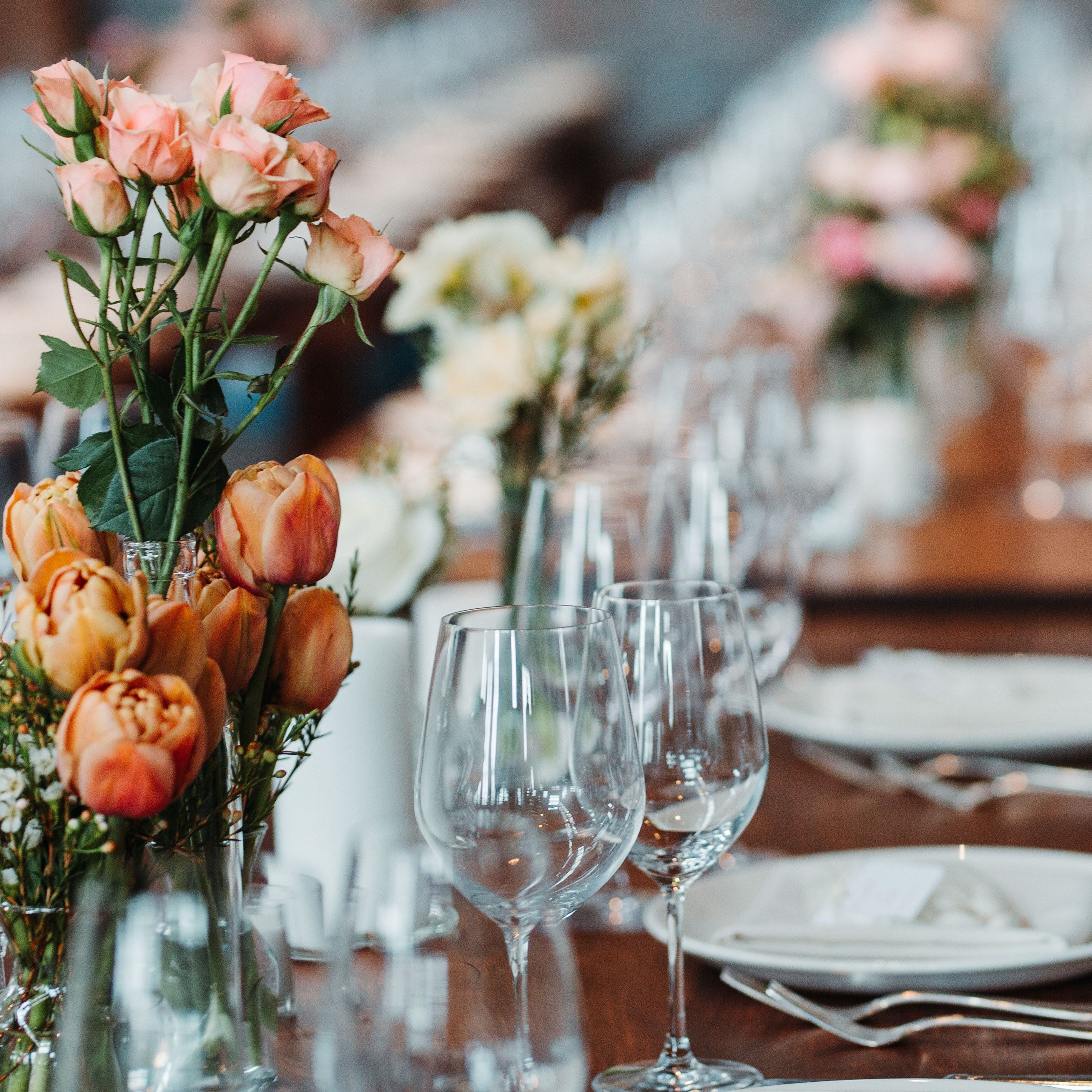 Tischgedeck mit Blumen auf langer Tafel.