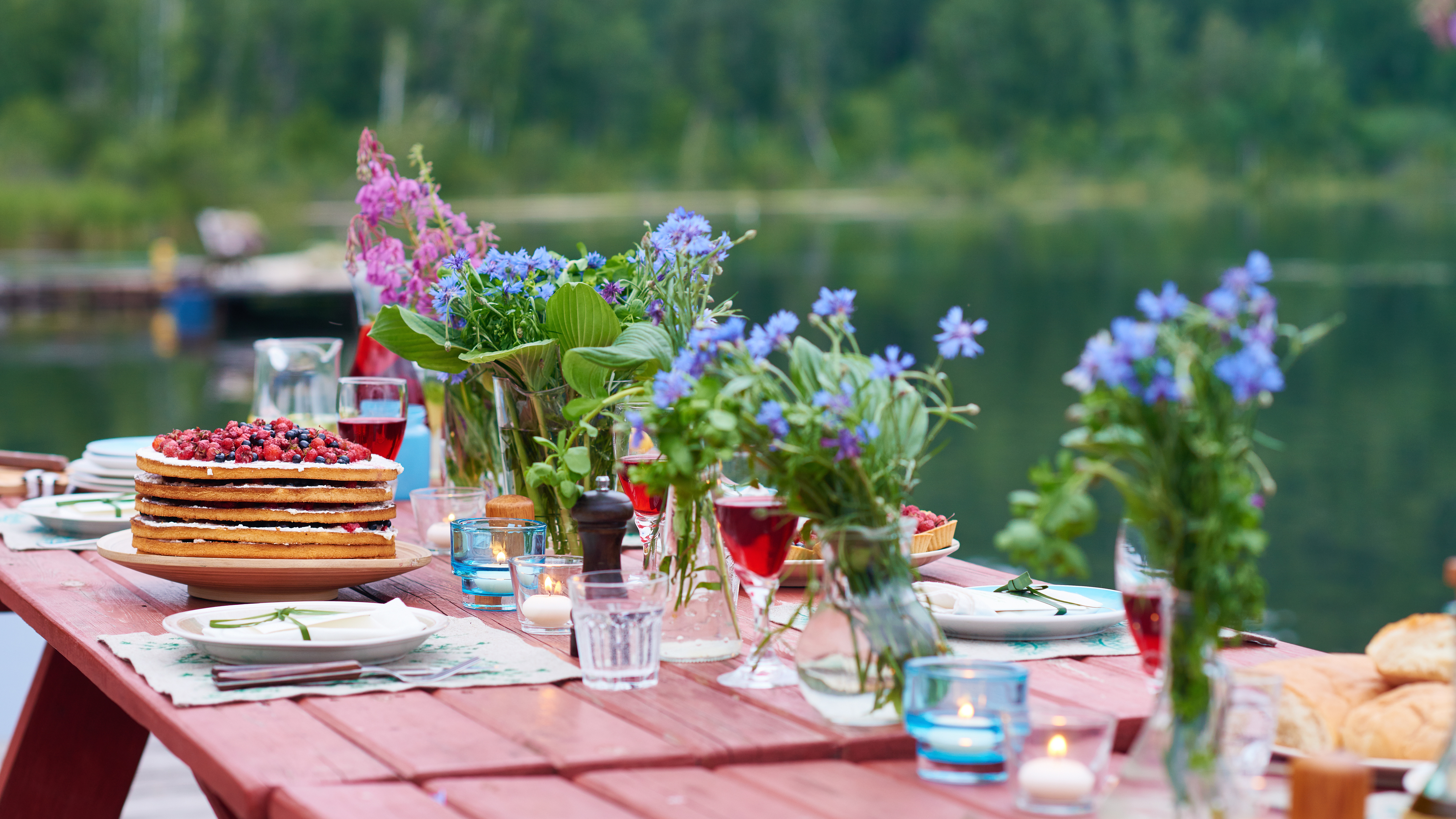 Sommerlich geschmückter Tisch mit Wiesenblumen und Essen 